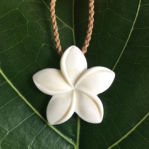 Colar com pingente esculpido em osso de búfalo branco com flor havaiana de plumeria e cordão trançado ajustável