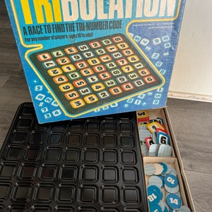 May include: A vintage board game called "Tribulation" with a black and white game board and colorful game pieces. The game is a race to find the tri-number code. The game is for any number of players and is suitable for ages 10 to adult.