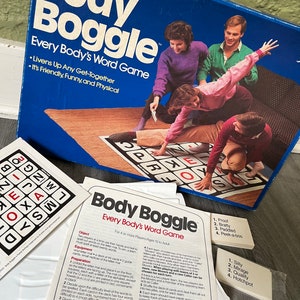 May include: A blue box game called "Body Boggle: Every Body's Word Game" with a picture of four people playing the game. The box has the words "Livens Up Any Get-Together" and "It's Friendly, Funny, and Physical" on it.