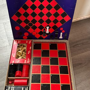May include: Checker and chess set in a box with red and black checkerboard, chess pieces, and checkers. The box lid says "Checker & Chess Set and Backgammon contains all the playing pieces".