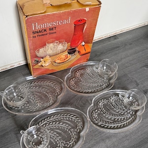Könnte beinhalten: Ein Vintage Homestead Snack-Set von Federal Glass, bestehend aus vier klaren Glastellern mit geprägtem Weizenmuster und vier passenden Glastassen. Das Set wird in der Originalverpackung aus Karton mit dem Text Homestead SNACK SET by Federal Glass geliefert.