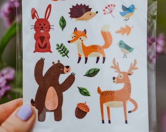 May include: A sheet of colorful woodland animal stickers, including a squirrel, fox, deer, bear, rabbit, hedgehog, and birds. The stickers are in a clear plastic sleeve, with a blurred floral background.