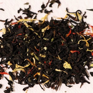 Pu&ograve; includere: Un primo piano di un blend di foglie di t&egrave; nero, pezzi di frutta secca e petali di fiori. Il blend di t&egrave; &egrave; un mix di tonalit&agrave; nere, gialle e rosse.