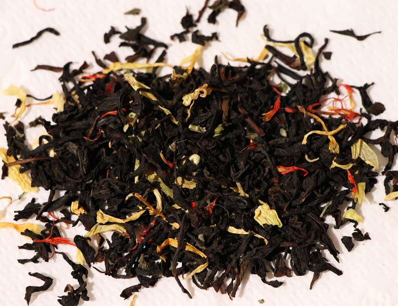 Pu&ograve; includere: Un primo piano di un blend di foglie di t&egrave; nero, pezzi di frutta secca e petali di fiori. Il blend di t&egrave; &egrave; un mix di tonalit&agrave; nere, gialle e rosse.