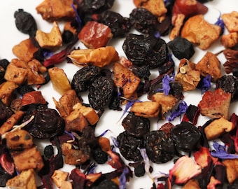 May include: A close-up of a mix of dried fruit and flower petals for tea. The mix includes dried apple, blueberries, and hibiscus flowers.