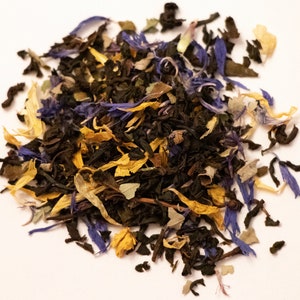 May include: A close-up of a blend of loose leaf tea with black tea, blue cornflower petals, and yellow calendula petals.