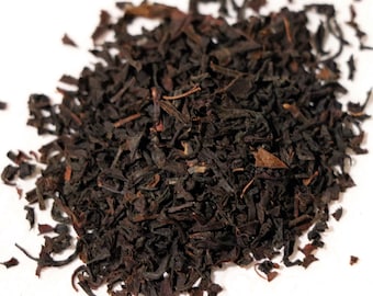 Könnte beinhalten: Lose schwarze Teeblätter, getrocknet und bereit zum Aufbrühen. Die Teeblätter sind dunkelbraun und haben eine leicht gekräuselte Form.