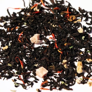 May include: A close-up of a black tea blend with dried fruit pieces and orange peel. The tea is loose leaf and ready to be brewed.
