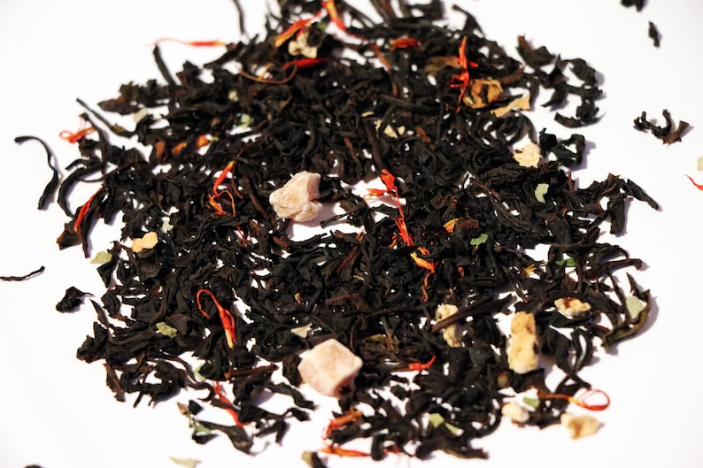 May include: A close-up of a black tea blend with dried fruit pieces and orange peel. The tea is loose leaf and ready to be brewed.