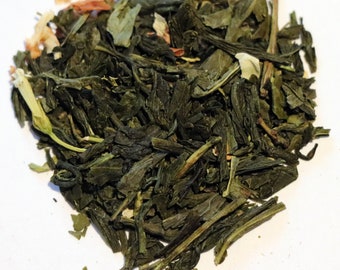 May include: A close-up of a pile of loose leaf green tea with white and orange flower petals.