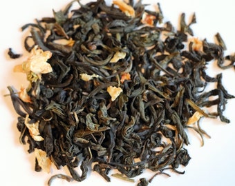 May include: A close-up of a pile of loose leaf green tea with dried orange peel and flower petals.