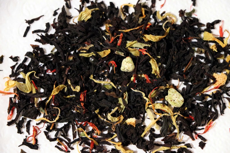 Pu&ograve; includere: Primo piano di un blend di foglie di t&egrave; nero, pezzi di frutta secca e petali di fiori. Il blend di t&egrave; &egrave; un mix di t&egrave; nero, scorza d'arancia secca, pezzi di mela secca e petali di carota selvatica.