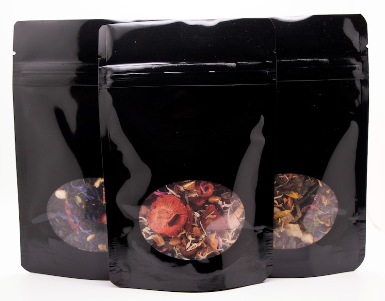 May include: Three black stand-up pouches with clear view windows. Each pouch contains a different blend of dried tea leaves and flowers.