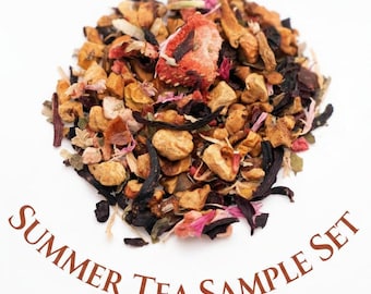 May include: A loose leaf tea blend featuring dried strawberry pieces, apple chunks, dark tea leaves, and pink flower petals. The text "SUMMER TEA SAMPLE SET" is printed in brown below the pile of tea ingredients on a plain white background.