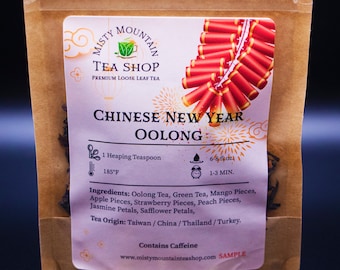 May include: A brown paper pouch with a red and gold label that says "Misty Mountain Tea Shop" and "Chinese New Year Oolong". The label also includes instructions for brewing the tea, such as the amount of tea to use, the water temperature, and the steeping time. The pouch contains a blend of loose leaf tea with fruit pieces and flower petals.