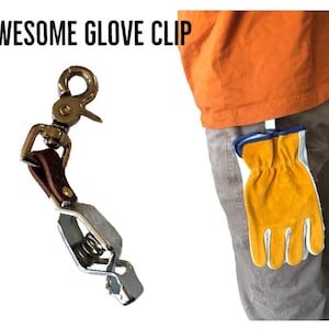 May include: A metal glove clip with a brown leather strap and a spring-loaded mechanism. The clip is attached to a belt loop and holds a yellow work glove.
