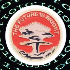 May include: A round pin with a red background and white border. The pin features a mushroom cloud design and the text "THE FUTURE IS BRIGHT" in white. The background is black with a digital binary code pattern.