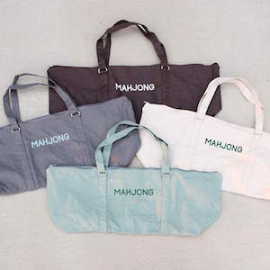 May include: Five tote bags in various colors: dark brown, gray, white, and light blue. Each bag has a rectangular shape with handles and the word "MAHJONG" printed on the front in a contrasting color.