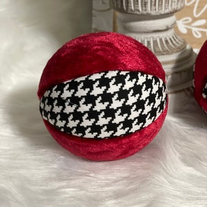May include: A red velvet ornament with a black and white houndstooth pattern.