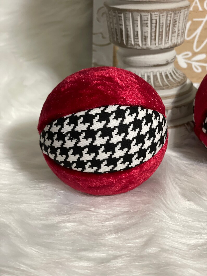 May include: A red velvet ornament with a black and white houndstooth pattern.