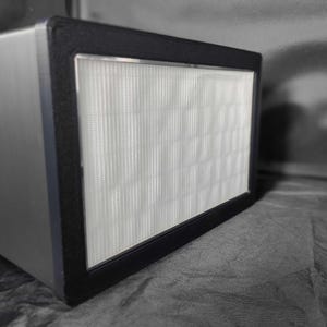 May include: A black rectangular air filter with a white filter inside. The filter is made of a fine mesh material.