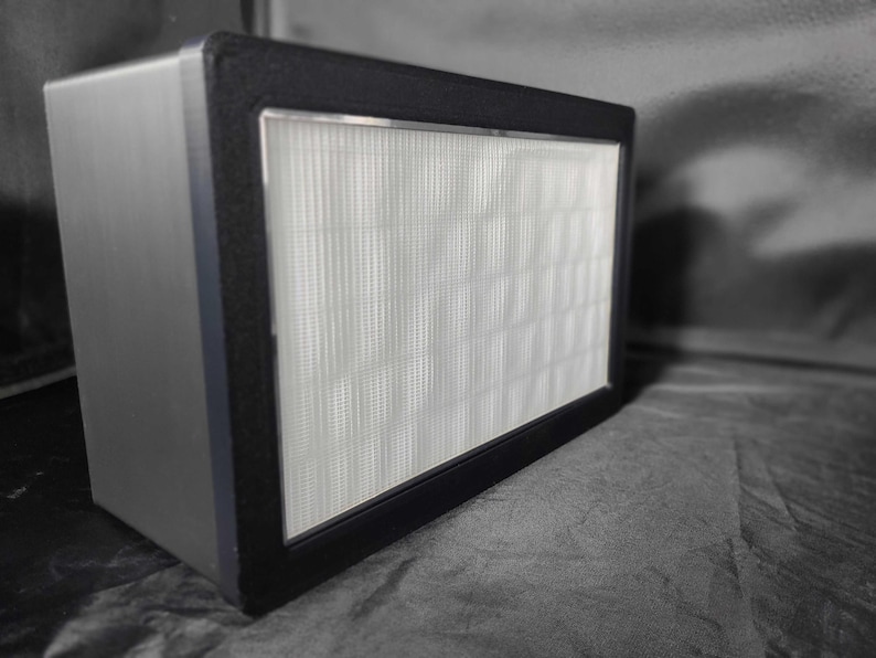 May include: A black rectangular air filter with a white filter inside. The filter is made of a fine mesh material.