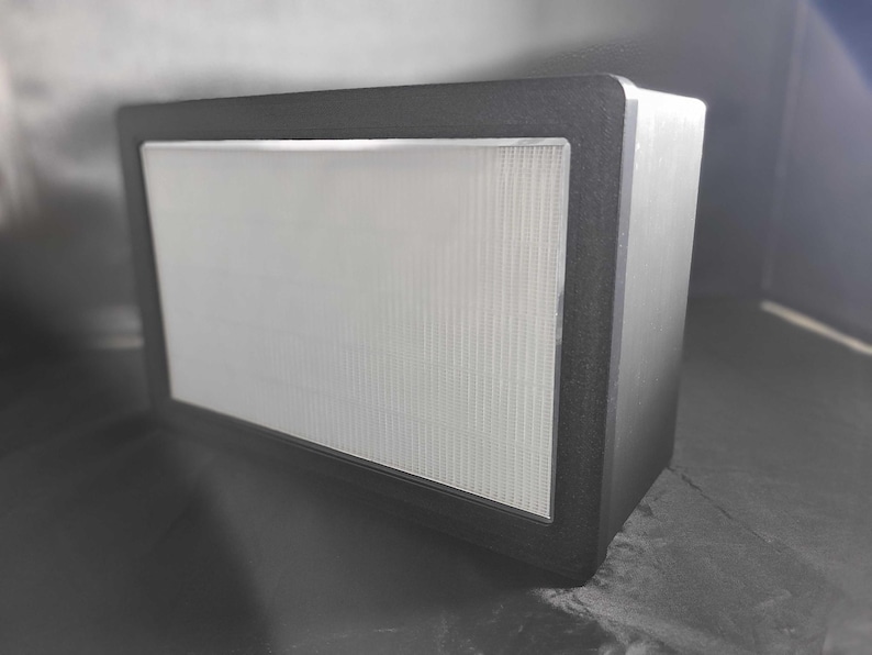 May include: A black rectangular speaker with a white speaker grille.