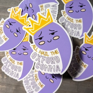 May include: Multiple purple stickers with a cartoon comma wearing a gold crown. The stickers say "All Hail the Oxford Comma".