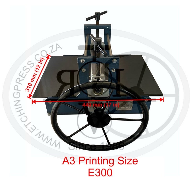 May include: A blue and black etching press with a 17-inch by 12-inch printing surface. The press has a large wheel for turning the press and a handle for adjusting the pressure. The press is labeled "A3 Printing Size E300".