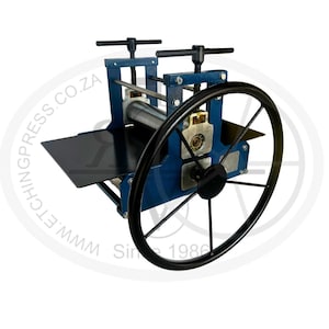 May include: A blue metal etching press featuring a large black handwheel, two top-mounted pressure adjustment handles, and a flat black bed plate. The machine includes silver rollers and metal side frames with the text WWW.ETCHINGPRESS.CO.ZA.