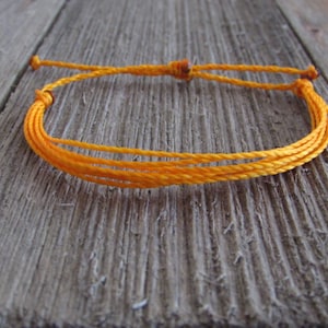 May include: A bright orange braided cord bracelet with adjustable closure.