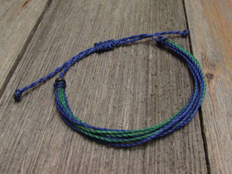 May include: A blue and green braided friendship bracelet with a knot closure.