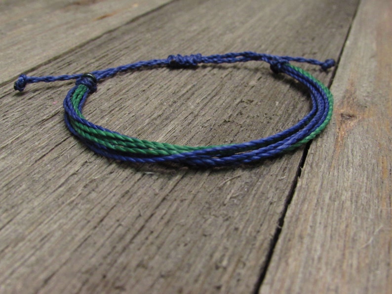 May include: A blue and green braided friendship bracelet with a silver clasp.