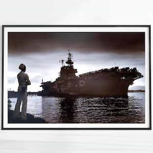 May include: A black and white photograph of a large ship docked at a pier. A person in a white uniform stands on the pier looking at the ship.