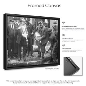 May include: Black and white photo of a group of men pouring liquid from large glass jugs. The photo is framed in a black frame and is ready to hang on a wall. The image is an example of a framed canvas print.