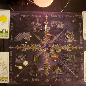 Peut inclure: &Eacute;talement de lecture de cartes de tarot sur un tissu violet avec des accents dor&eacute;s. Les cartes sont dispos&eacute;es en cercle avec l'As de Pentacles, l'As de B&acirc;tons, l'As de Coupes et l'As d'&Eacute;p&eacute;es visibles. Les cartes sont entour&eacute;es de divers charmes et bibelots.