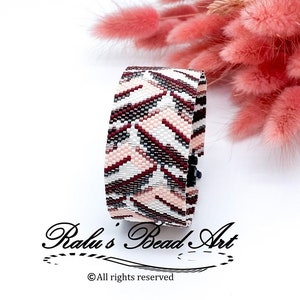 Könnte beinhalten: Ein weißes, rosa und braunes Perlenarmband mit geometrischem Muster. Das Armband liegt auf einer weißen Oberfläche mit einem Strauß rosa getrockneter Blumen dahinter. Der Text "Ralu's Bead Art" und "© Alle Rechte vorbehalten" ist unterhalb des Armbands sichtbar.