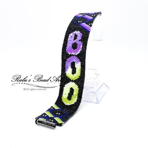 May include: A black beaded bracelet with a colourful "BOO" design. The bracelet is made with small, colourful beads and has a silver clasp.