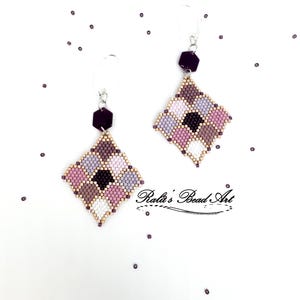 May include: A pair of diamond-shaped beaded earrings featuring a geometric pattern of purple, pink, white, and tan seed beads. Each earring hangs from a dark purple hexagonal bead and a silver-toned hook. The text Ralu's Bead Art is visible.
