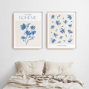 May include: Two framed prints with blue floral illustrations on a cream background. The left print has the text "GALERIE BOHEME" and a single bouquet of flowers. The right print has the text "LES FLEURS" and a pattern of scattered flowers.