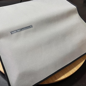 Könnte beinhalten: Ein graues Stoff-Mauspad mit schwarzem Rand und dem aufgedruckten Text "TANDY 1000".