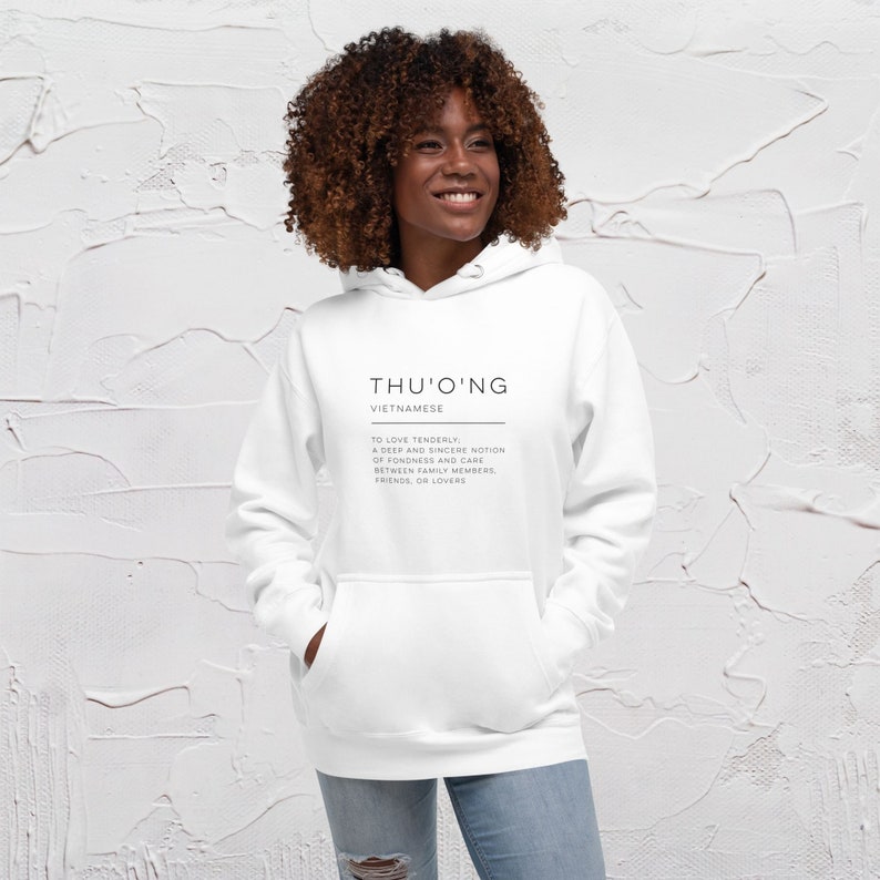 Pode incluir: Camisola de capuz branca com a palavra vietnamita "Thu'o'ng" impressa na frente, significando "amar ternamente". A defini&ccedil;&atilde;o da palavra tamb&eacute;m est&aacute; impressa abaixo.