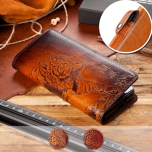 Puede incluir: Una cartera de cuero marrón con un grabado detallado de un tigre. La cartera tiene un efecto de color degradado, que va del marrón oscuro a un tono más claro. Tiene un cierre de botón a presión y un pequeño detalle de texto.