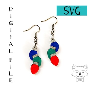 Può includere: Orecchini in legno a forma di lampadine natalizie blu, verdi e rosse. Hanno ganci per le orecchie color bronzo. La parola "SVG" è in un rettangolo turchese. Le parole "DIGITAL FILE" sono scritte verticalmente.