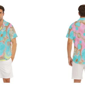 May include: A short-sleeved button-down shirt with a colourful abstract print. The shirt has a relaxed fit and a collar. The model is wearing white shorts.