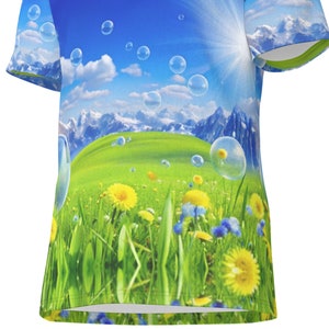 May include: A blue and green t-shirt featuring a graphic print of a field of dandelions and bubbles floating over a mountain range.
