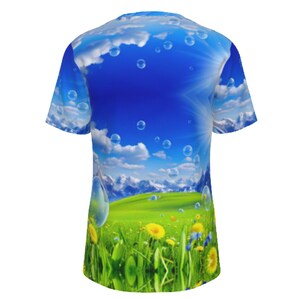 May include: A blue and green t-shirt with a graphic print of a field of grass, flowers, and mountains with a blue sky and white clouds with bubbles floating in the sky.