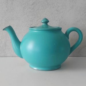 May include: A teal blue ceramic teapot with a rounded body and a simple knob on the lid.