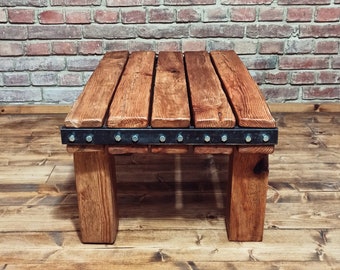 Wooden table made of old Vintage beams. Handmade massive coffee table with metal fittings and visible screws.