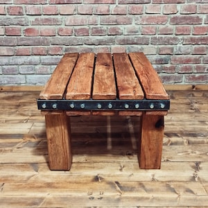 Wooden table made of old beams Vintage. Hand-made massive coffee table with metal fittings and visible screws.